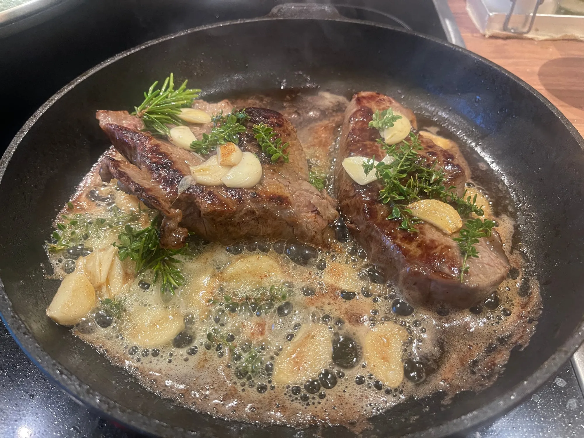 Steak mit Butter, Knoblauch und Kräutern in der Pfanne